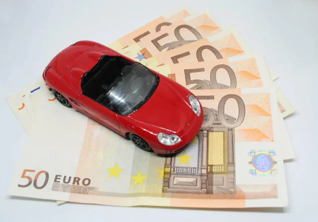 Modellino auto rossa su banconote da 50 euro. Un simbolo di pignoramento auto cointestata e delle sue conseguenze economiche.