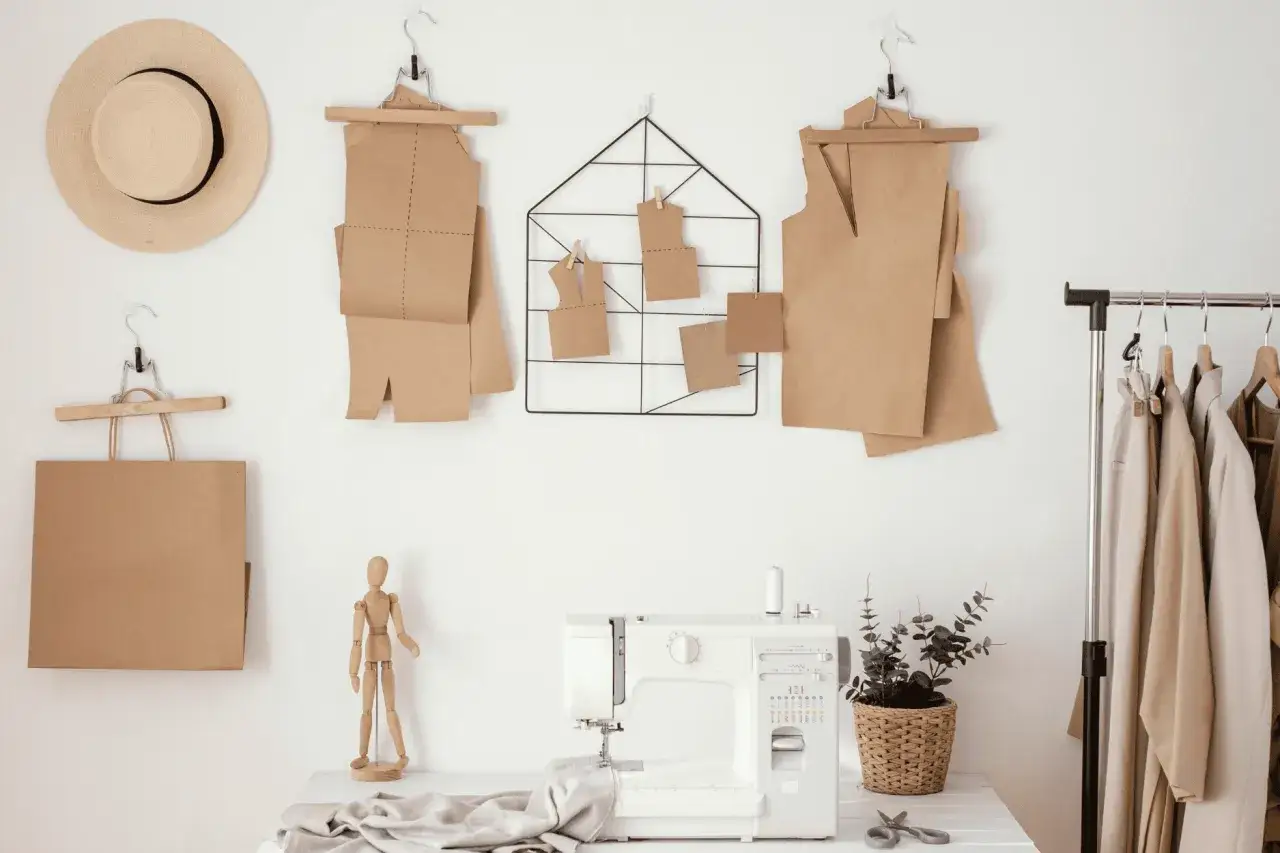 Patrones de papel marr&oacute;n colgados en la pared, como se llama el papel para hacer patrones. M&aacute;quina de coser y ropa en un perchero.
