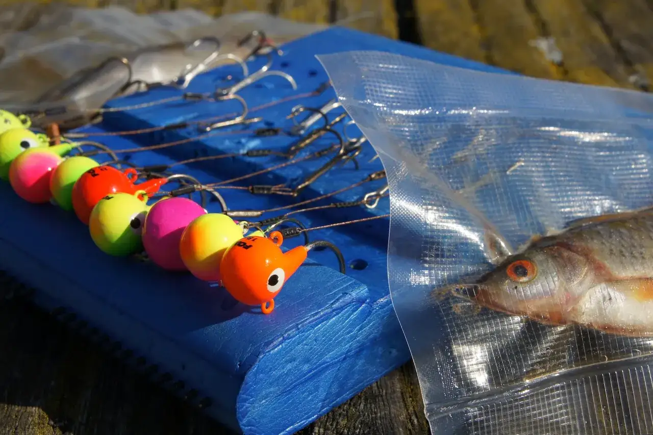 Bunte Köder für das Fireball Angeln liegen bereit. Ein kleiner Fisch in einer Tüte wartet auf seinen Einsatz.