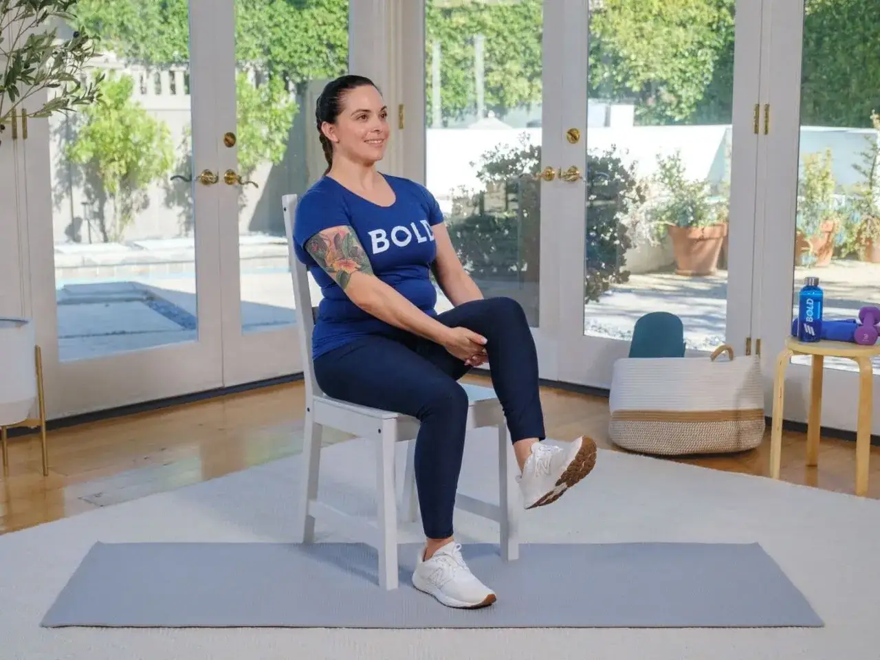 Fiche technique gym douce pour personne &acirc;g&eacute;e : une femme assise sur une chaise, jambe lev&eacute;e, pour un exercice simple et efficace.