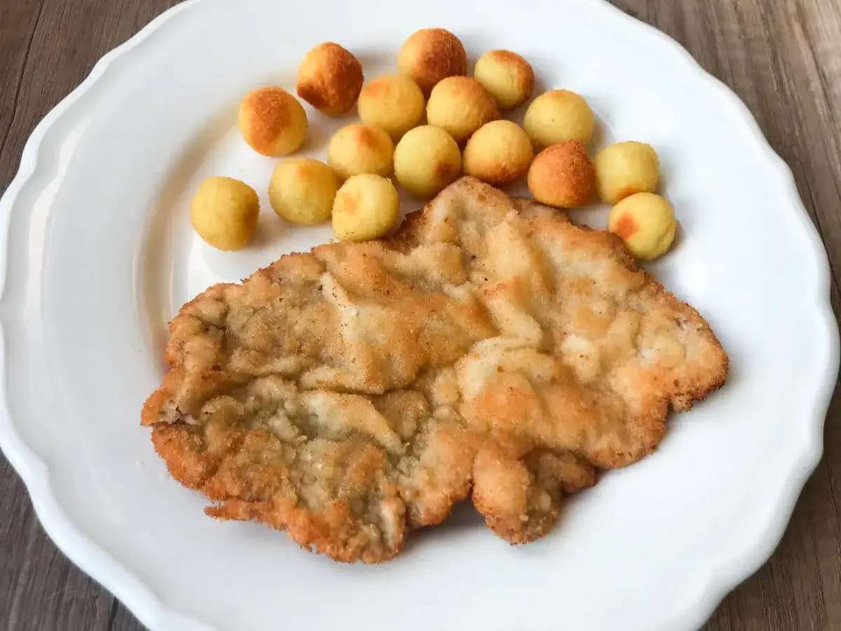 Chrupiący schabowy w panko, idealnie usmażony, podany z małymi, złocistymi ziemniaczkami. Pyszny obiad gotowy!