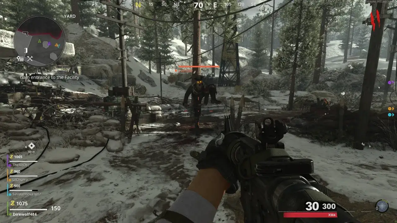 Gracz w Call of Duty Cold War walczy z zombie w zaśnieżonym lesie, celując z karabinu.