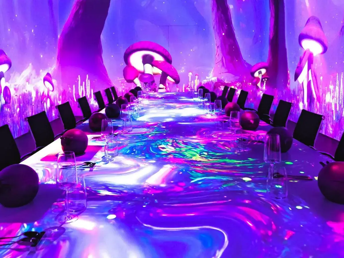 Un restaurante sensorial con proyecciones de hongos gigantes y luces vibrantes. Una mesa larga y elegante, lista para una experiencia inmersiva.