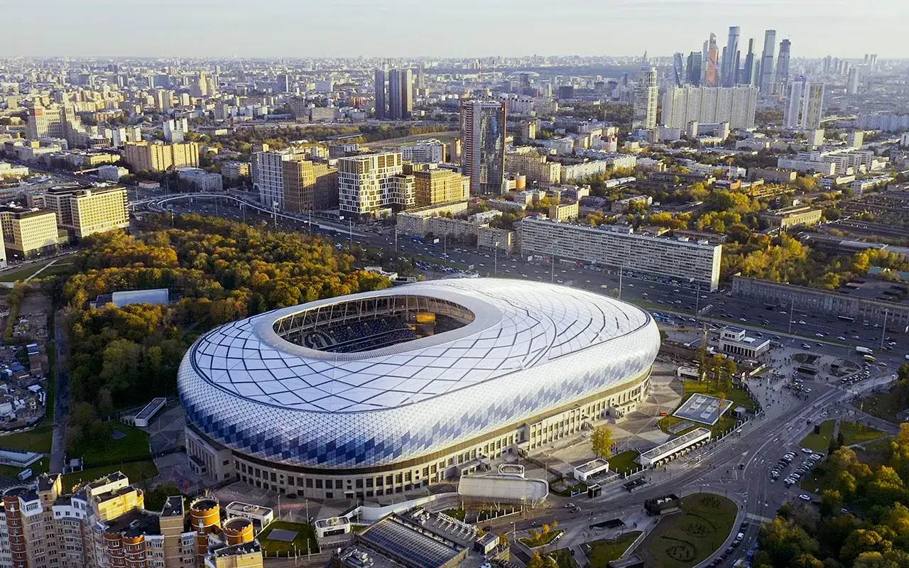 Nowoczesny stadion w Moskwie, dom klubu piłkarskiego z Moskwy, otoczony zielenią i miejską zabudową.