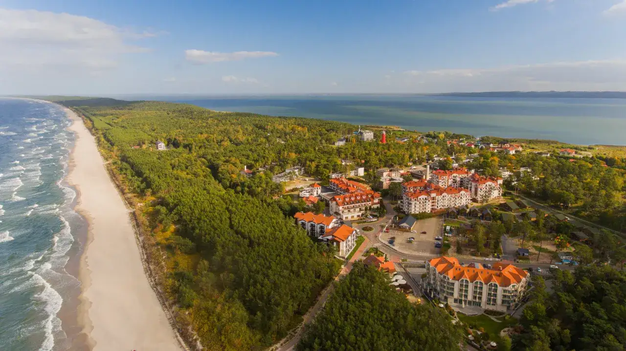 Widok z lotu ptaka na miejscowości na Mierzei Wiślanej. Plaże, lasy i zabudowania hotelowe tworzą malowniczy krajobraz.