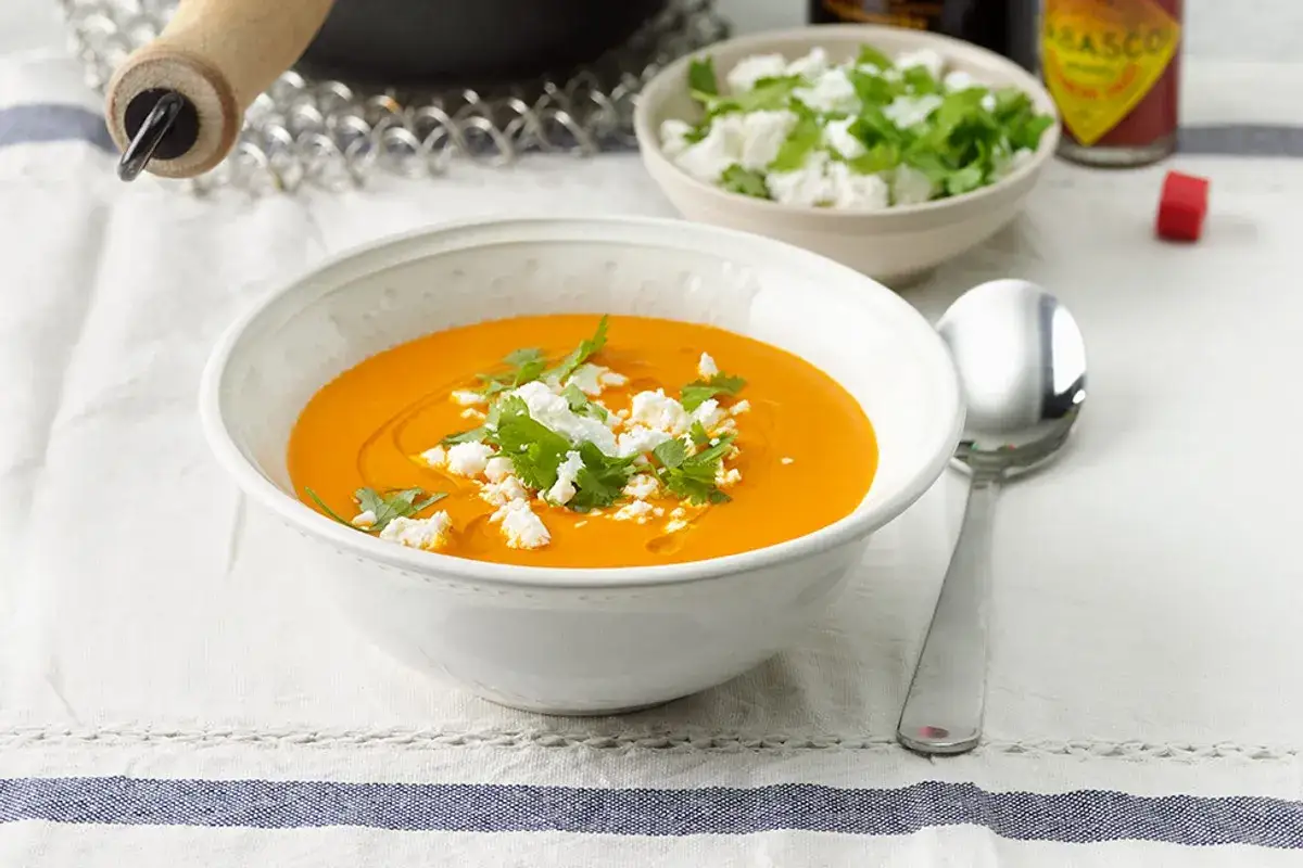 Kr&auml;mig orange soppa med fetaost och koriander, perfekt f&ouml;r ett enkelt selleri recept. En sked ligger bredvid.