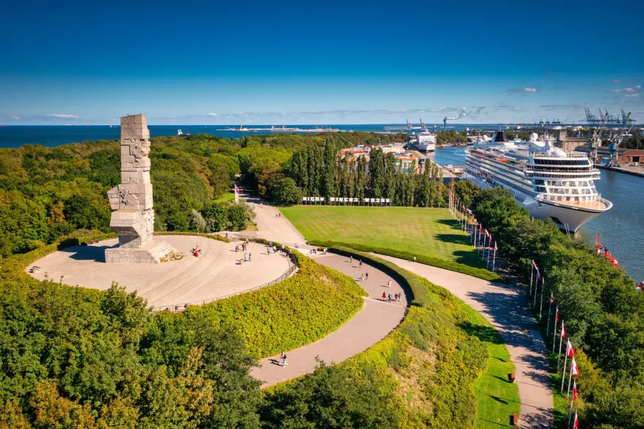 Pomnik Obrońców Wybrzeża i port, z którego słynie Gdańsk, z zacumowanym statkiem wycieczkowym.