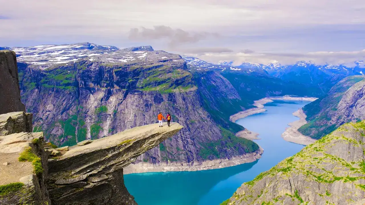 Två personer njuter av utsikten från Trolltunga, en ikonisk klippavsats. En fantastisk plats för att vandra i Norge.
