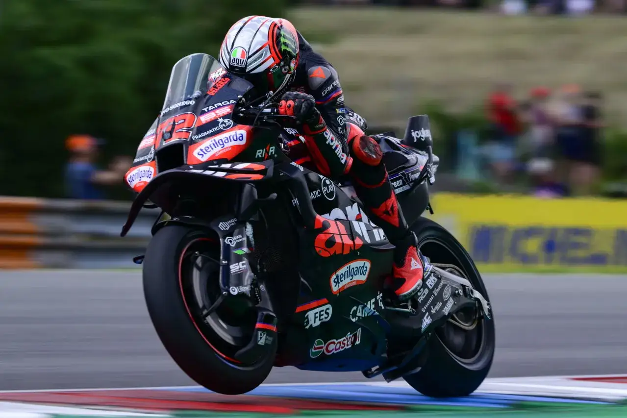 Piloto de MotoGP en Aprilia negra y roja, con el dorsal 29, compitiendo en una carrera. Las concesiones MotoGP permiten estas máquinas.