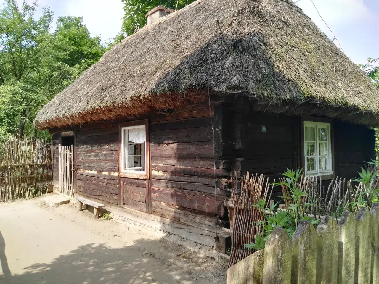 Drewniana chata z krytym strzechą dachem, część skansenu w Dziekanowicach.