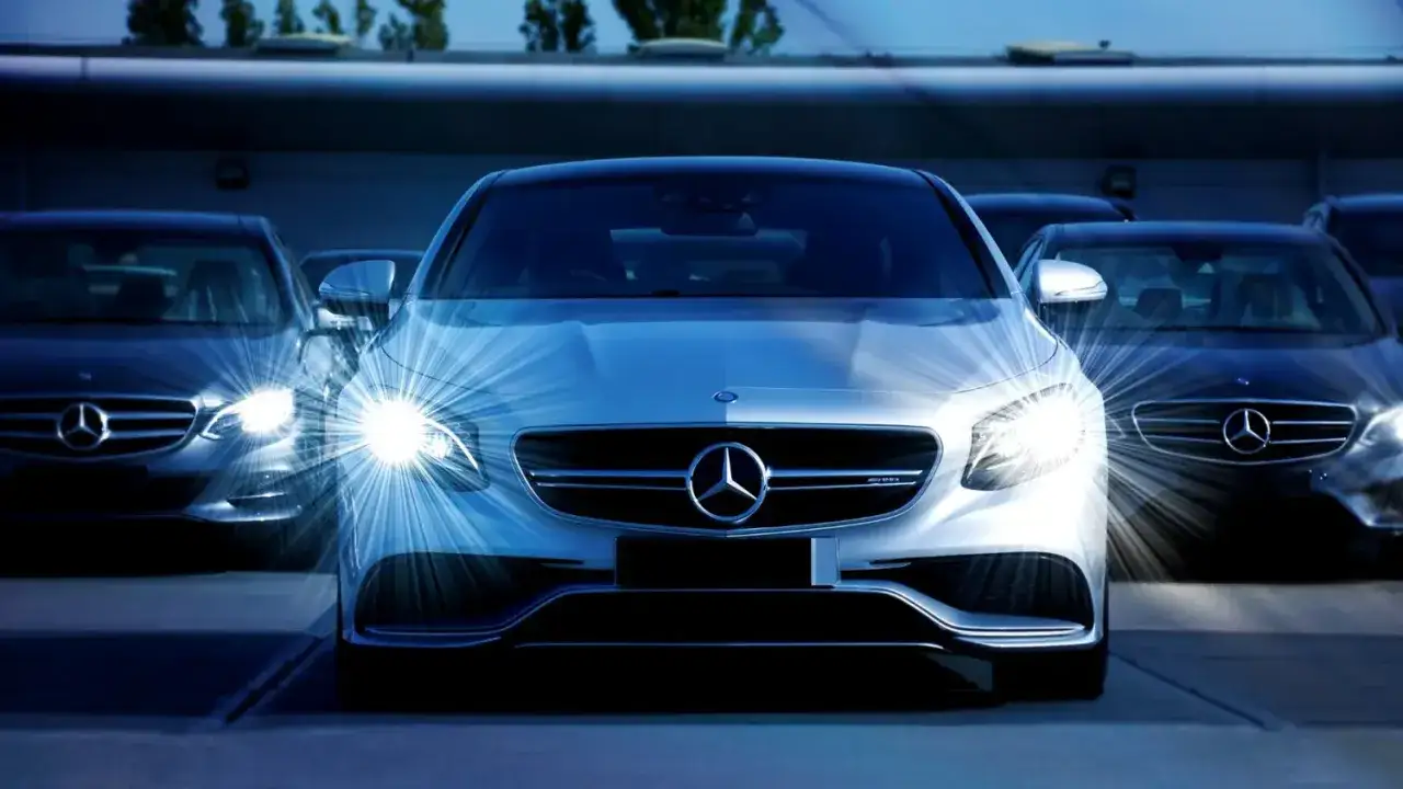 En rad Mercedes-bilar st&aring;r uppradade, med den i mitten i fokus. Trots att det &auml;r en sn&aring;l bil, lyser dess str&aring;lkastare starkt.