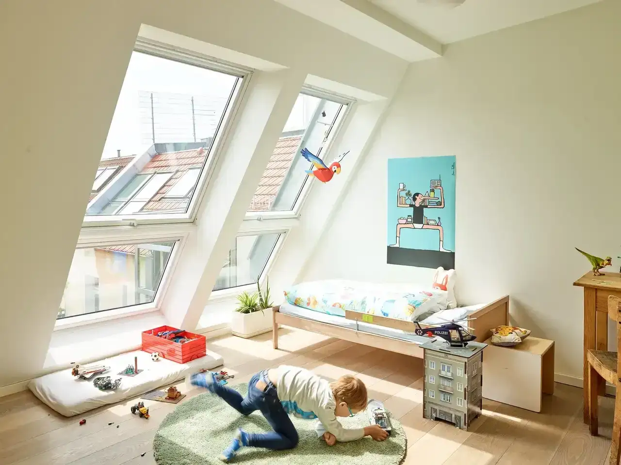 Ein Junge spielt in einem hellen Kinderzimmer unter dem Dach. Tolle **Kinderzimmer Dachboden Ideen** mit Dachfenstern und Spielzeug.