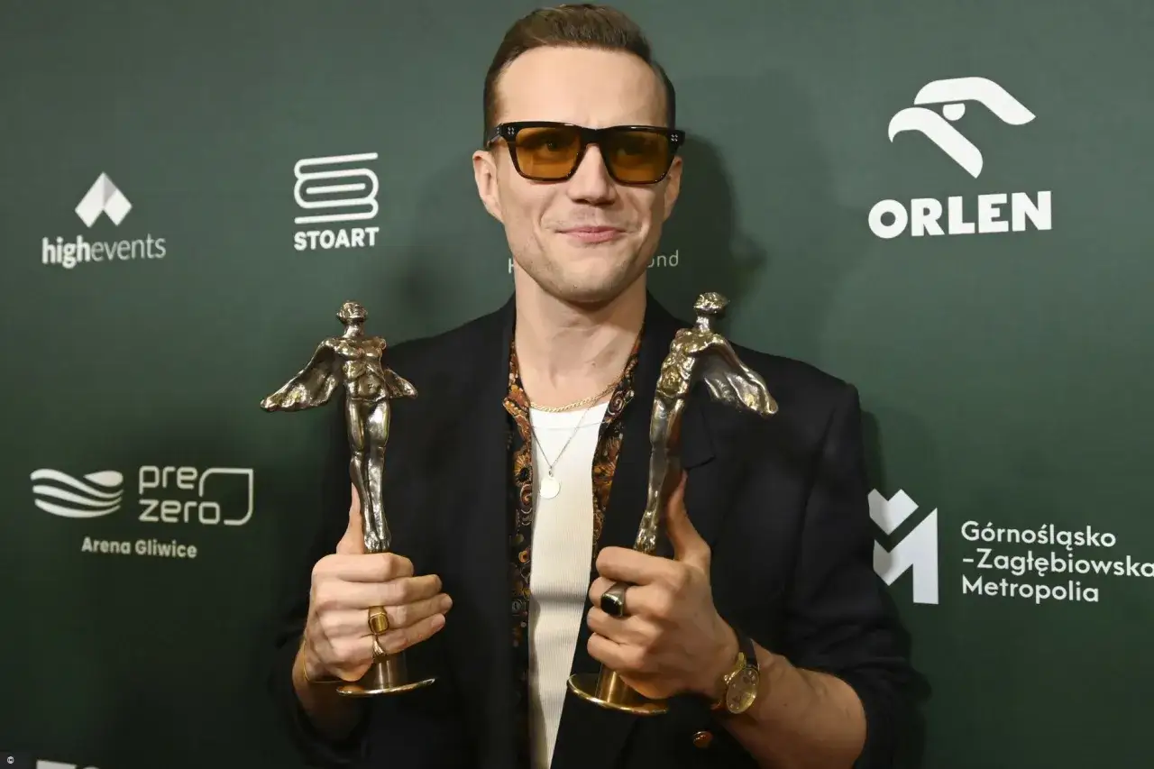 Mężczyzna w okularach z dwoma statuetkami, zdobywca nagród w plebiscycie.