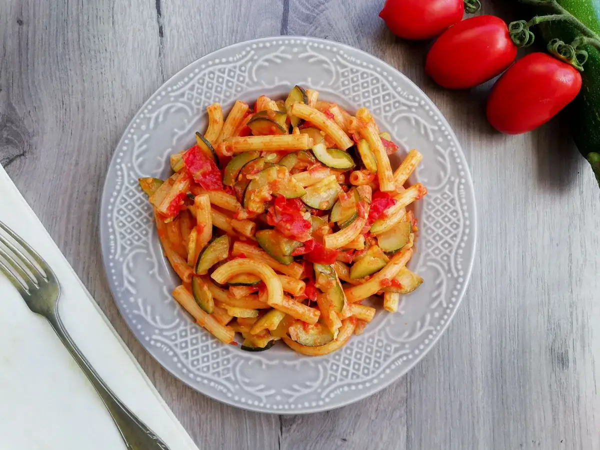 Piatto di pasta con zucchine e pomodorini, un classico estivo.