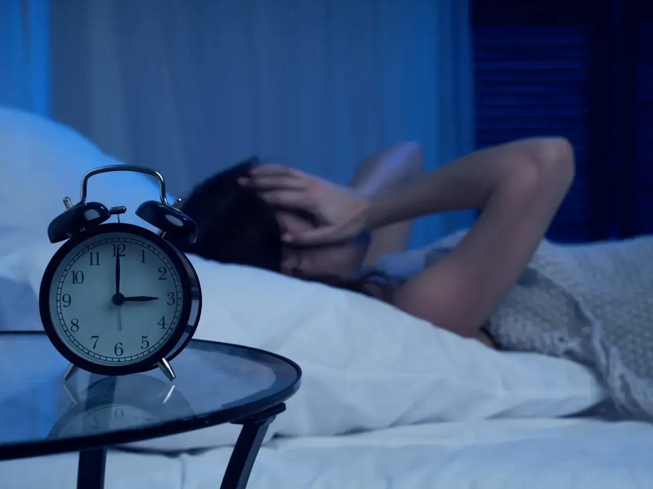 Son las 4 de la ma&ntilde;ana y no puedo dormir. La persona en la cama se tapa la cara con las manos, frustrada. El despertador marca las 4:00.