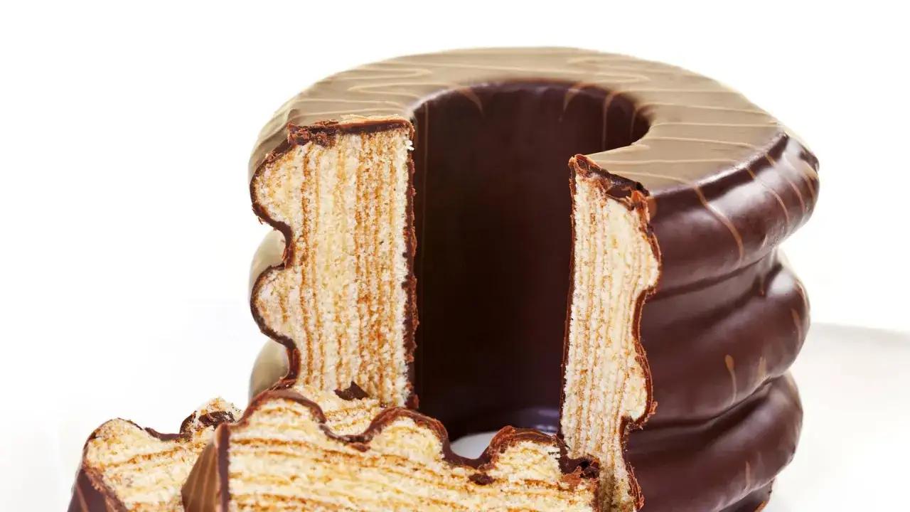 Ein angeschnittener Baumkuchen mit Schokoladenglasur, der die vielen Schichten zeigt. Perfekt für ein Baumkuchen Rezept.