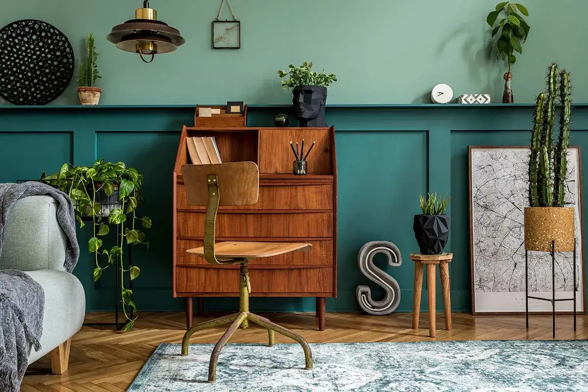 Stylowy gabinet z meblami w stylu retro. Drewniane biurko, zielona ściana i rośliny tworzą przytulny klimat.