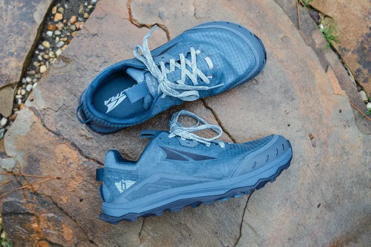 Blaue Altra Lone Peak hallux wanderschuhe liegen auf nassen Steinen. Perfekt für jedes Abenteuer!