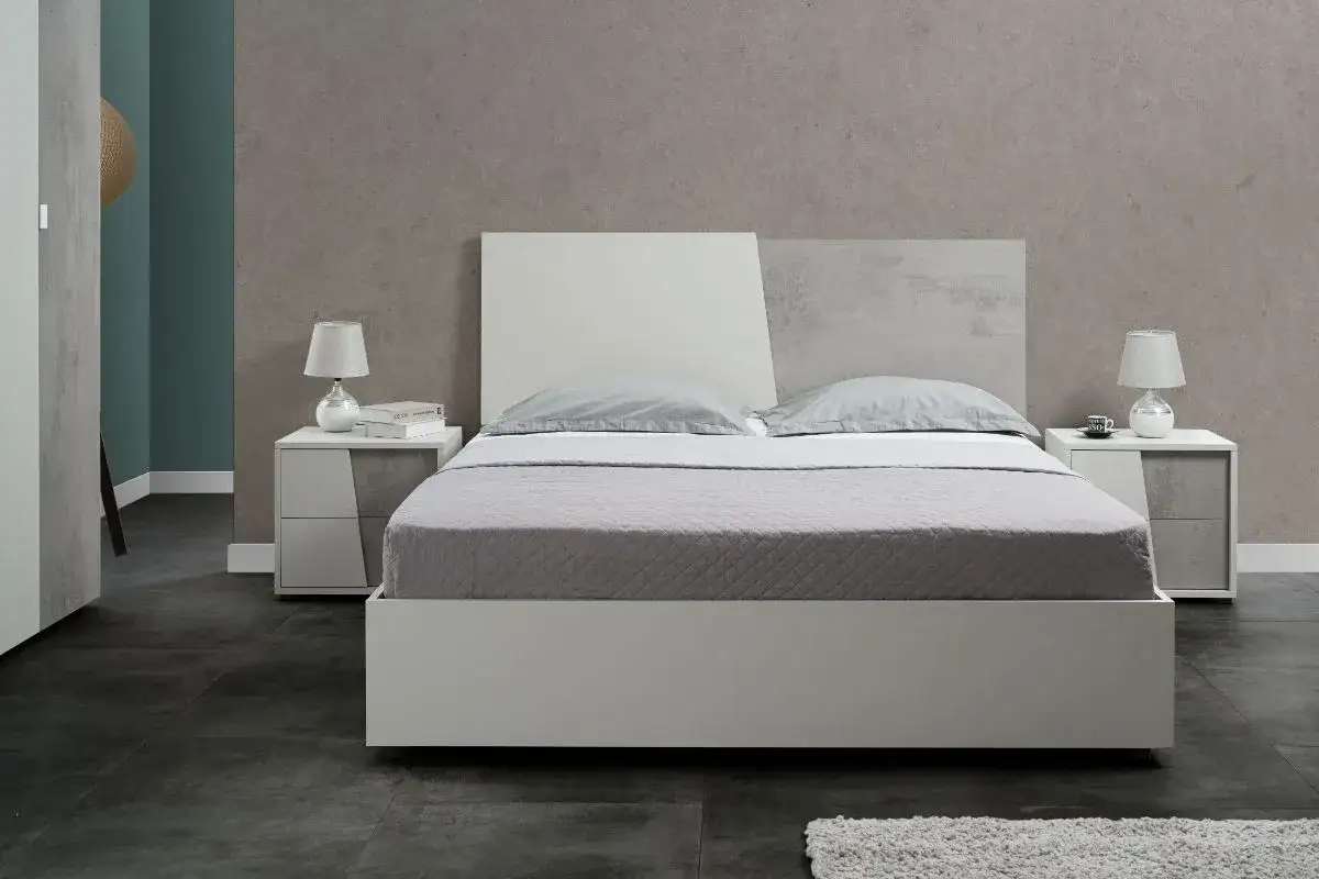 Camera da letto moderna con letto bianco e testiera bicolore. L'abbinamento colori camera da letto &egrave; sui toni del grigio e bianco, con comodini coordinati.