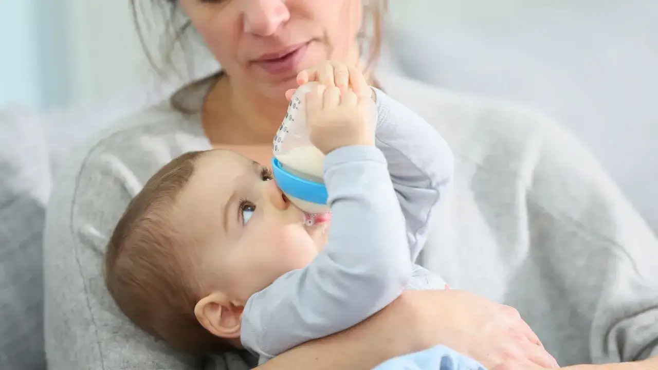 Mama karmi butelką 7-miesięczne dziecko, które jeszcze nie siedzi.
