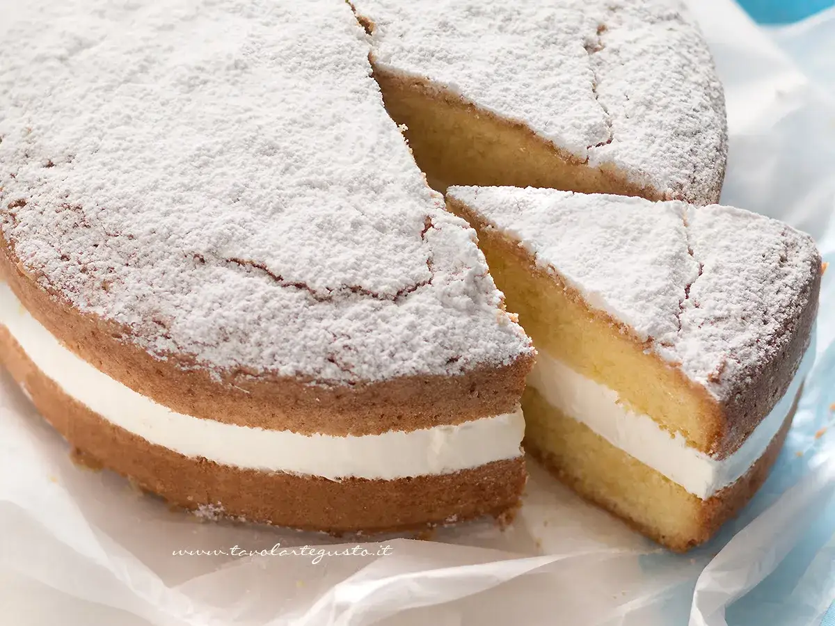 Una fetta di torta paradiso, soffice e spolverata di zucchero a velo, con un ripieno cremoso.