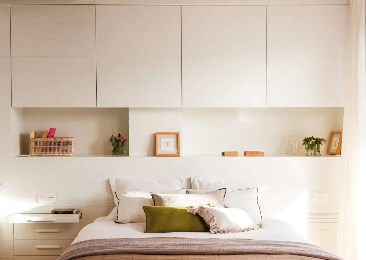 Cama con almohadas y mantas, estantes con decoración y armarios empotrados. Una habitación que inspira paz, ¿cuanto mide una habitación normal?
