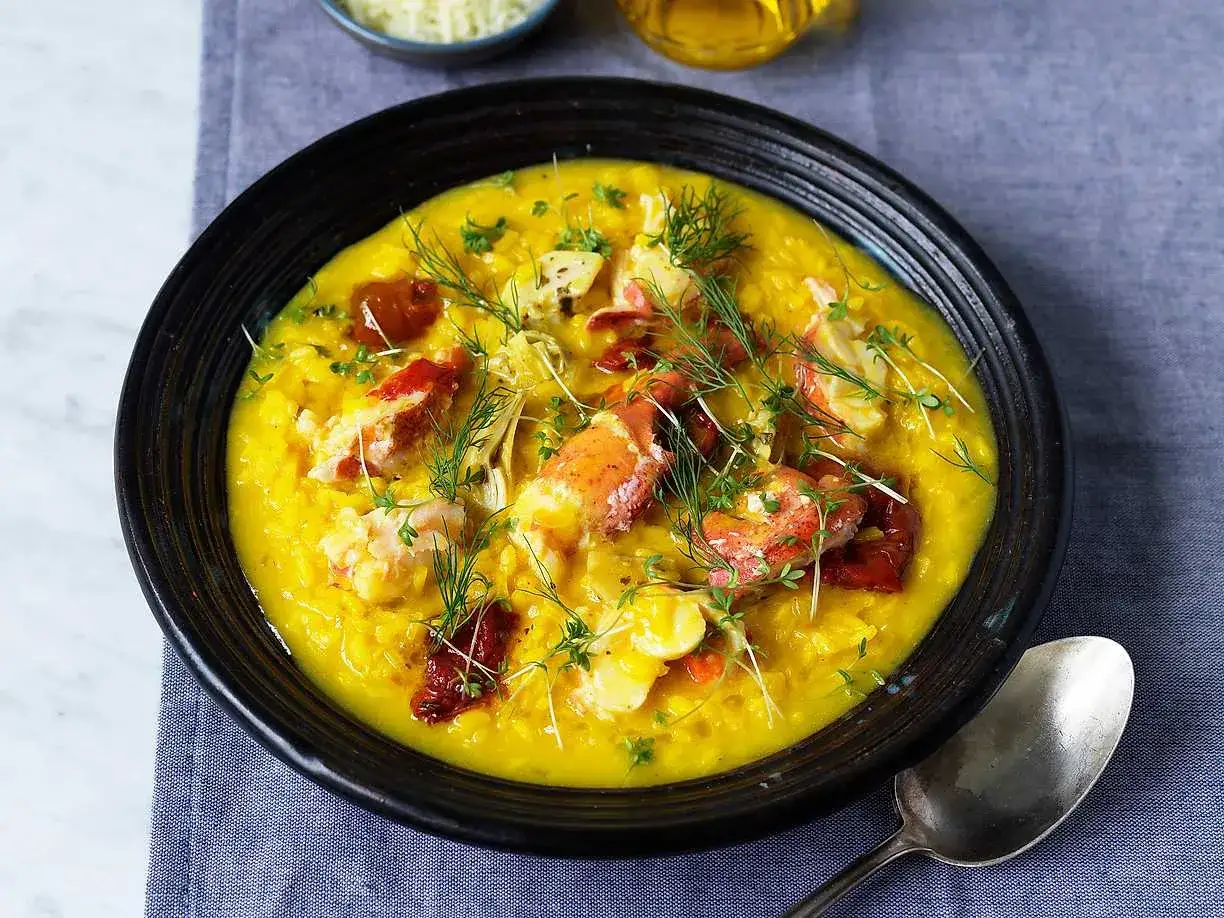 En kr&auml;mig risotto milanese med hummerbitar, toppad med dill och soltorkade tomater.