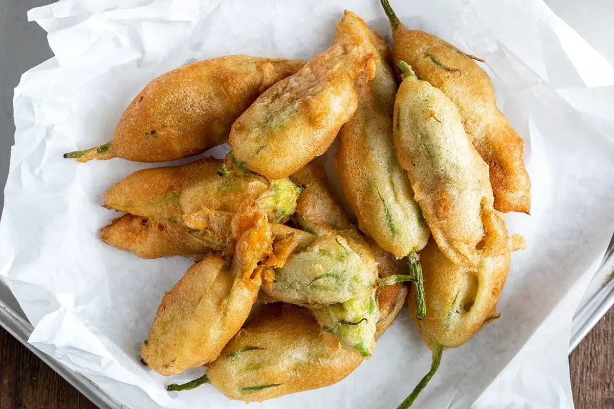 Fiori di zucca in padella con pangrattato, dorati e croccanti, pronti per essere gustati.