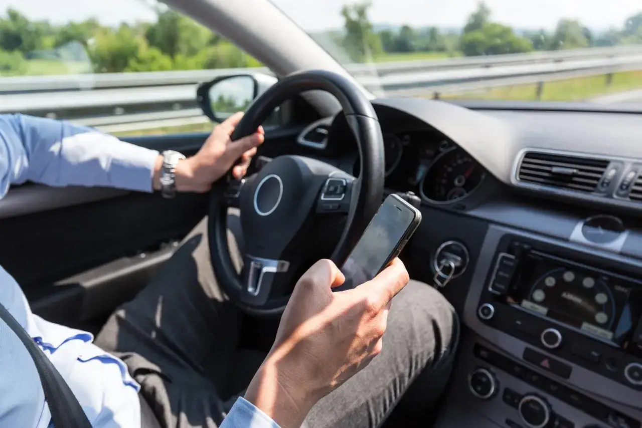 Conducteur distrait, utilisant son téléphone au volant. Une conduite dangereuse qui peut coûter 6 points sur le permis.