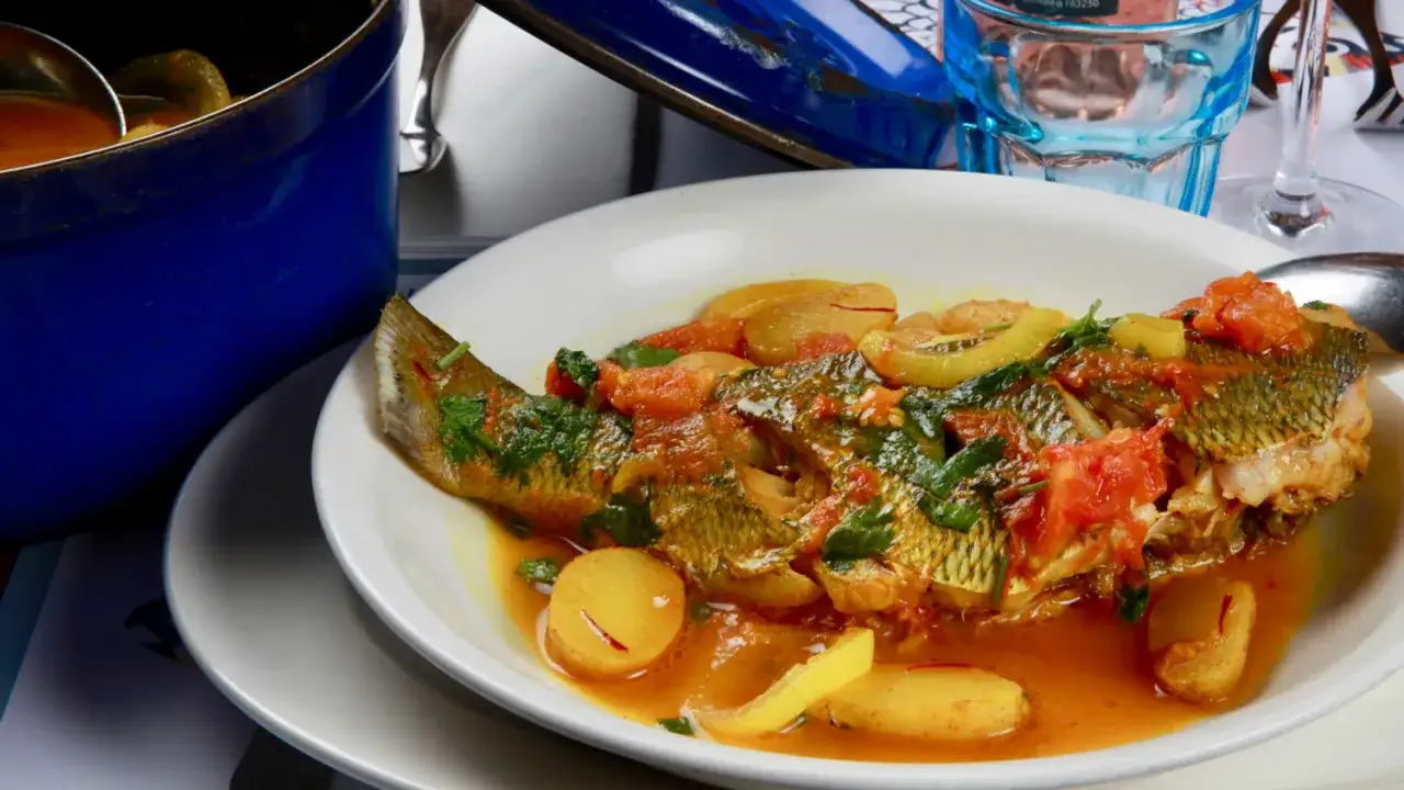 La dorade royale, un poisson entier cuisiné avec des tomates, des pommes de terre et des herbes, baigne dans une sauce savoureuse.