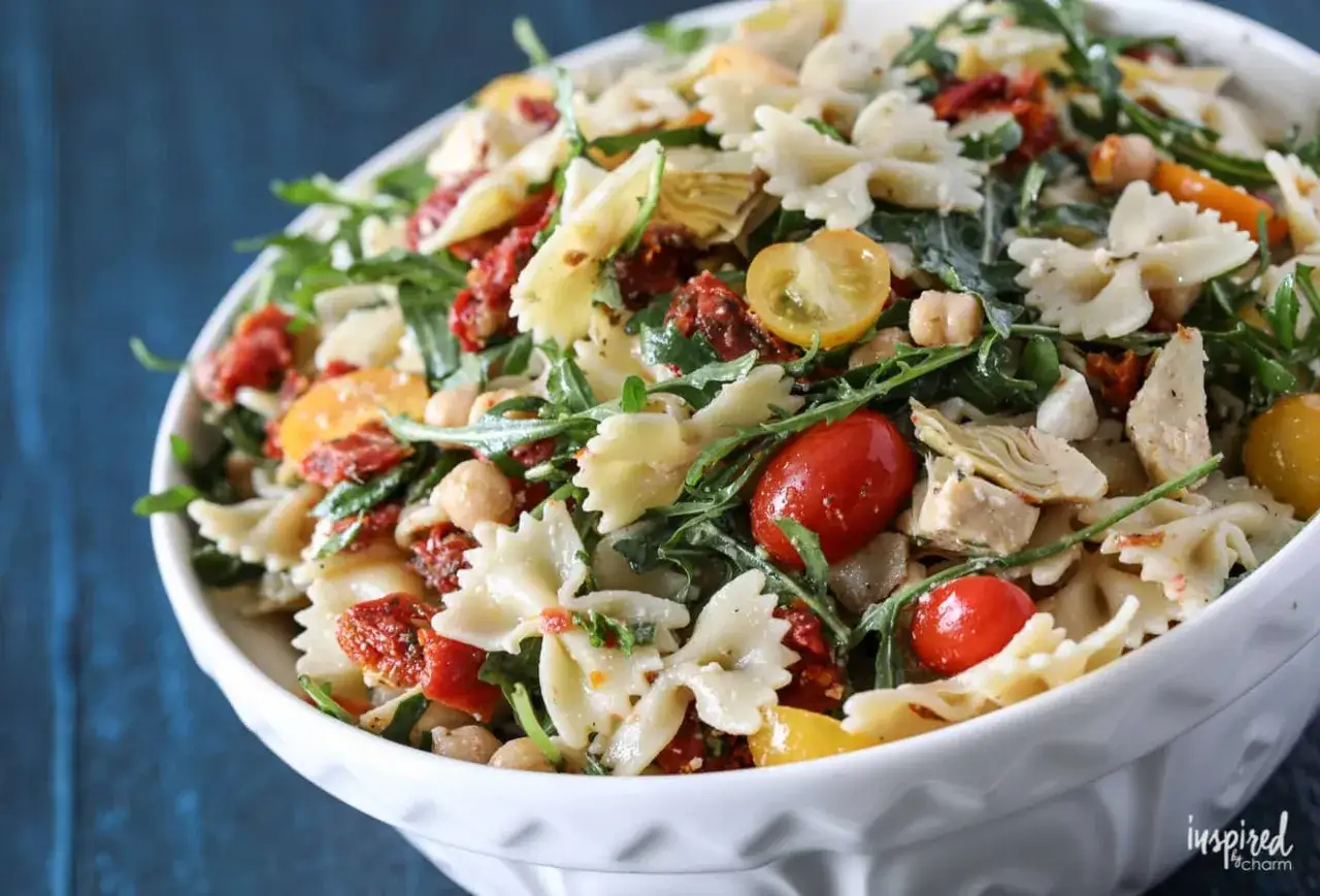 Ein bunter Nudelsalat mit Farfalle, Kichererbsen, Rucola, Artischockenherzen und vielen sonnengetrockneten Tomaten.