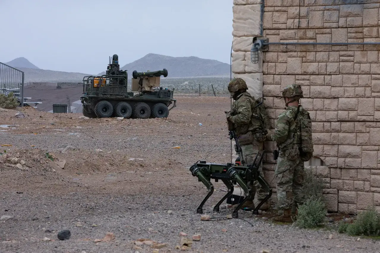 Żołnierze z robotem-psim i pojazdem bojowym, jak w grach podobnych do Battlefield. Pustynny teren.