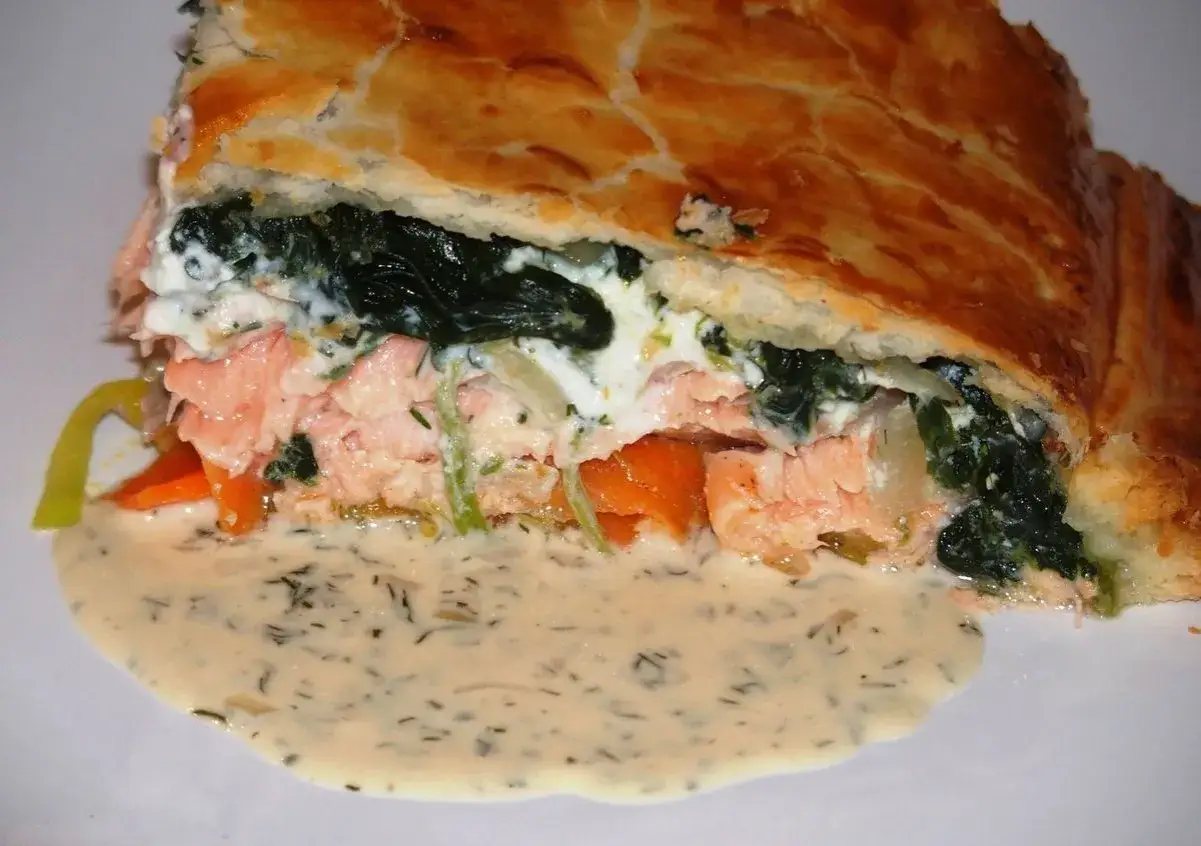 Tranche de saumon en croûte dorée, garnie d'épinards et de sauce crémeuse. Un délice visuel et gustatif.