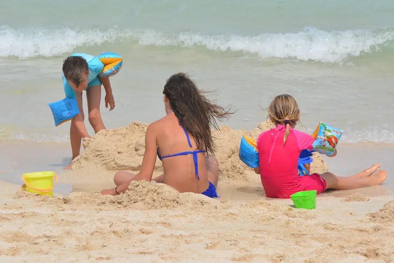 Bambini si divertono in spiaggia, godendosi le vacanze al mare con secchielli e braccioli.