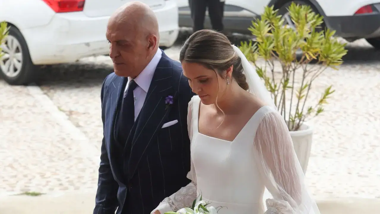 Un hombre con traje a rayas acompa&ntilde;a a una novia con velo y ramo de flores. Un momento emotivo de la boda de Irene Matamoros.