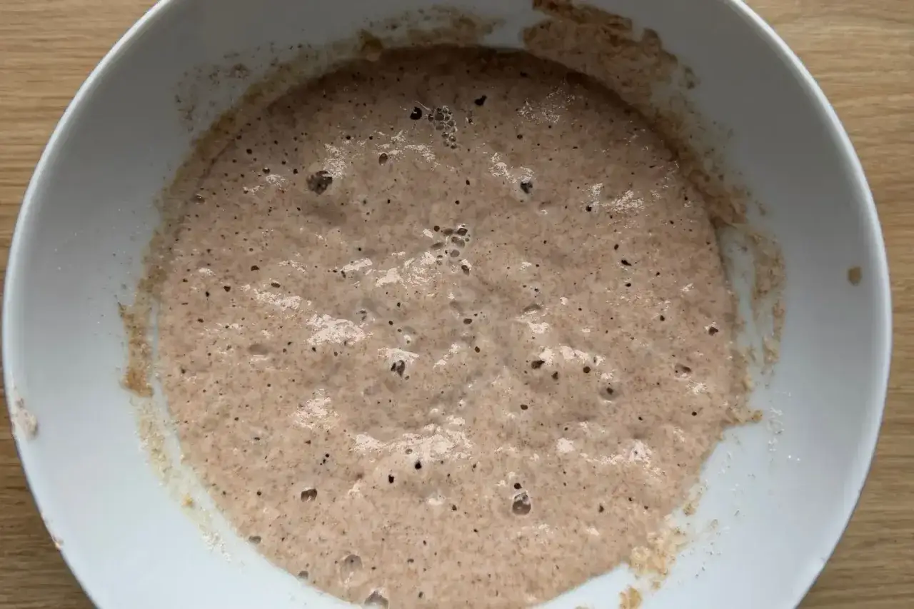 Ein blubbernder Sauerteigansatz in einer wei&szlig;en Sch&uuml;ssel, bereit f&uuml;r das Brotbacken.