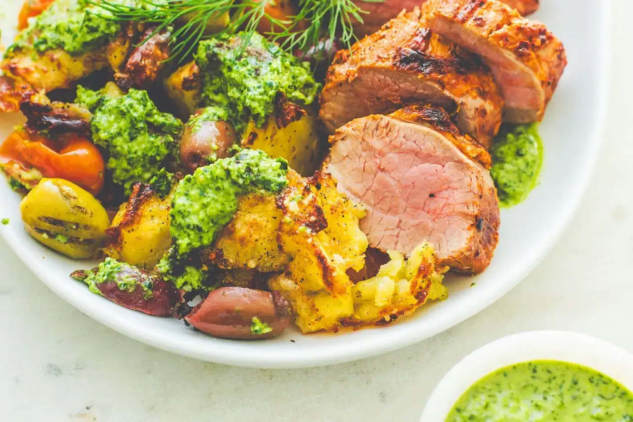 Pieczony schab z ziemniakami i oliwkami, polany zielonym pesto. Idealny pomysł, co zrobić z pesto, by danie było pyszne!