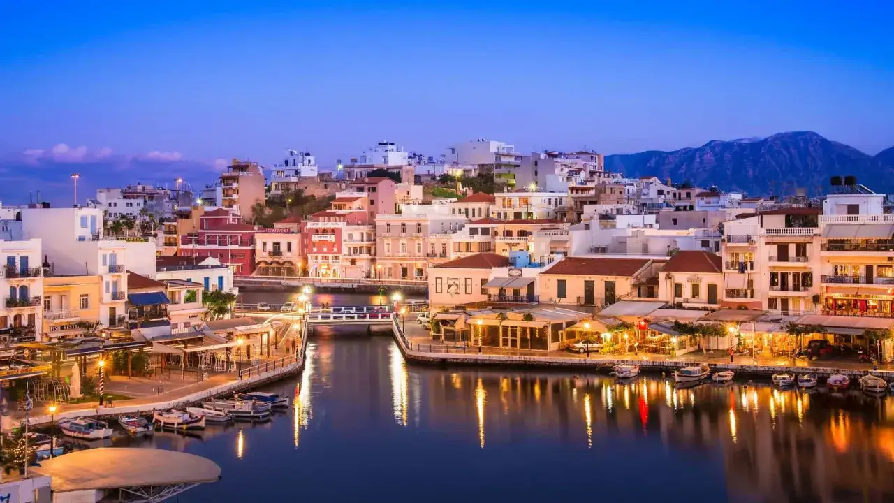 Agios Nikolaos cosa vedere: pittoresca vista del lago Voulismeni con barche e ristoranti illuminati al crepuscolo.