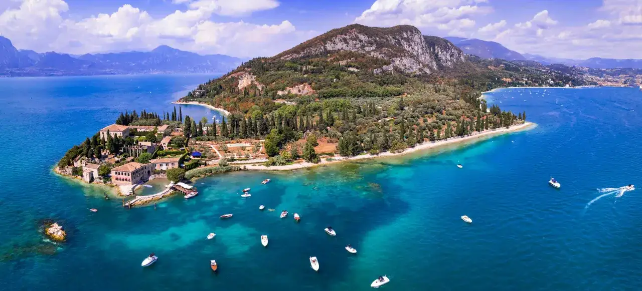 La baia delle sirene, con le sue acque cristalline e la vegetazione lussureggiante, incanta con un borgo antico e barche che solcano il lago.
