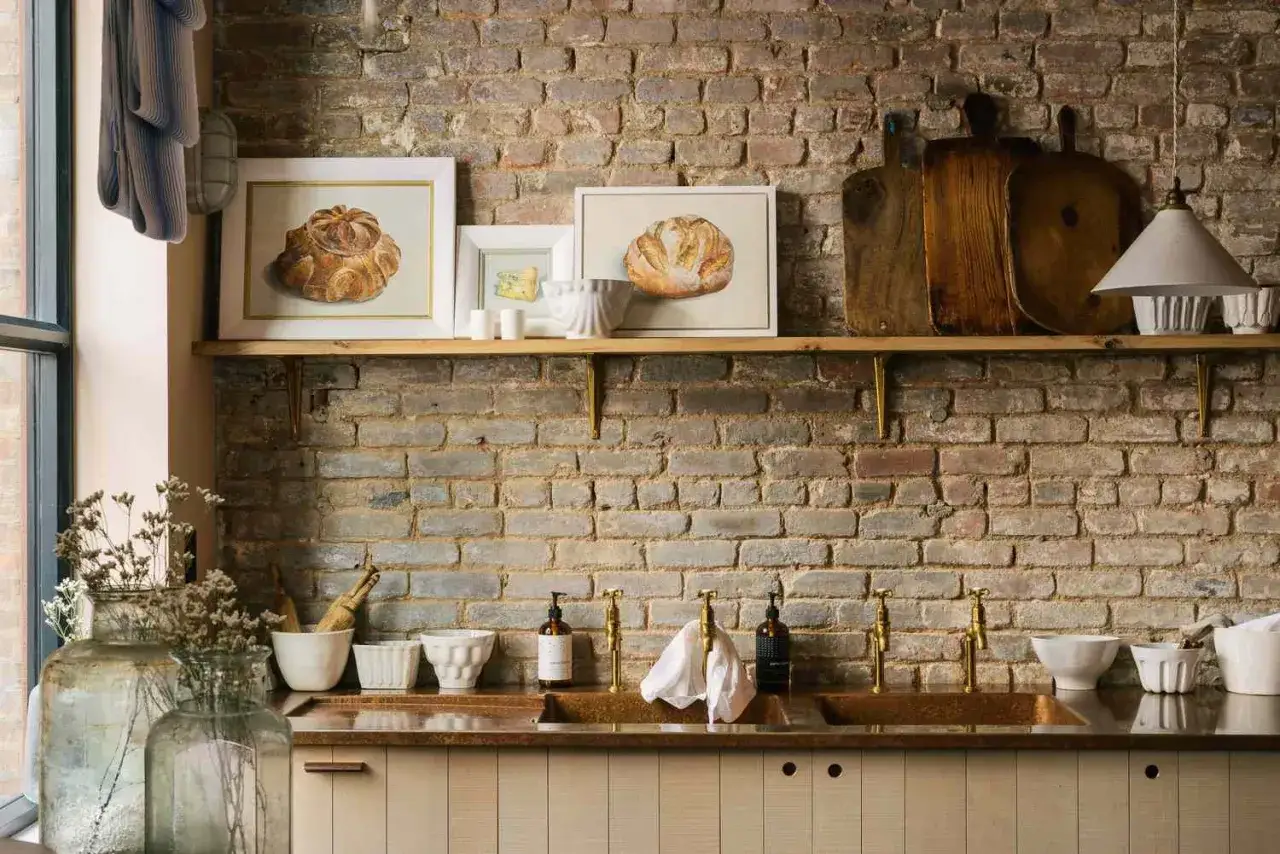 Inspirujące pomysły na p&oacute;łki ścienne: obrazy chleba, deski do krojenia i ceramiczne misy nad kuchennym blatem.