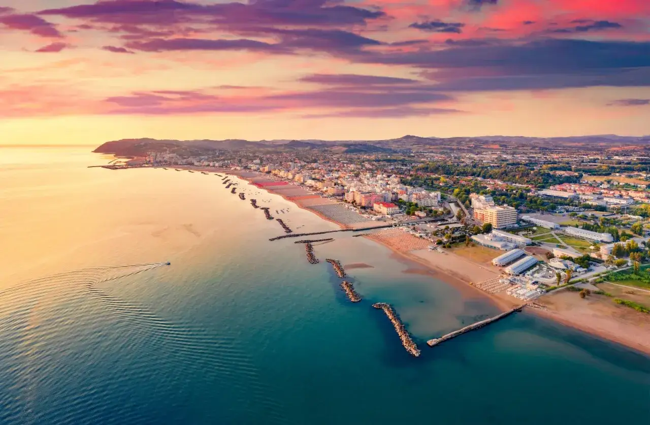 Alba colorata sul mare di Cattolica, con la costa e le colline sullo sfondo.
