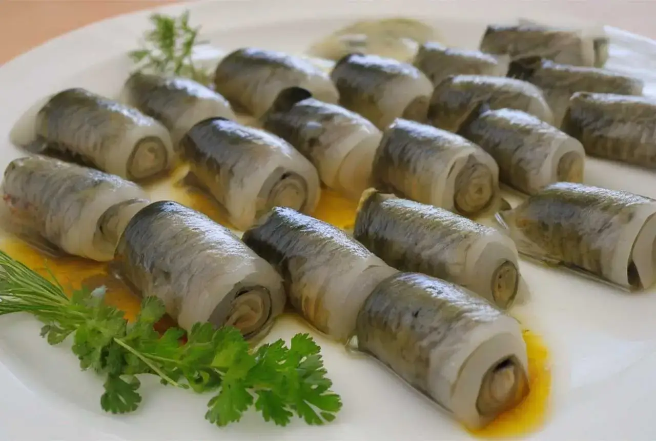 Rolle des Rollmops Fisch auf einer wei&szlig;en Platte, garniert mit Dill und Petersilie.