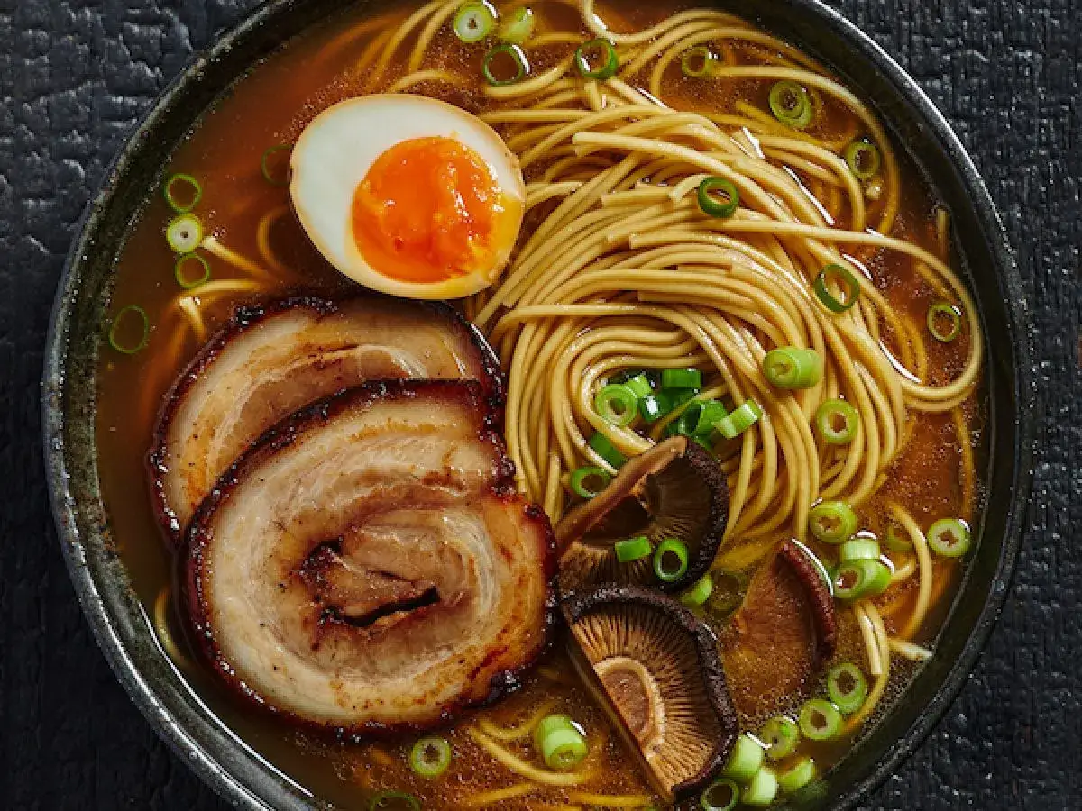 Miseczka aromatycznego ramen: makaron, jajko na pół, plastry wieprzowiny, grzyby shiitake i szczypiorek. Pyszne danie, które rozgrzewa.
