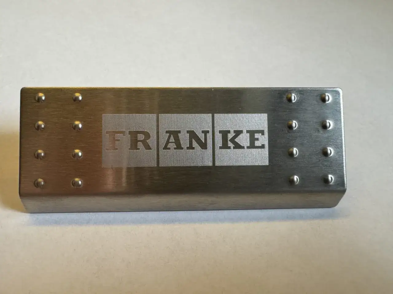 Metalowa zaślepka przelewu zlewozmywaka z wygrawerowanym logo FRANKE.