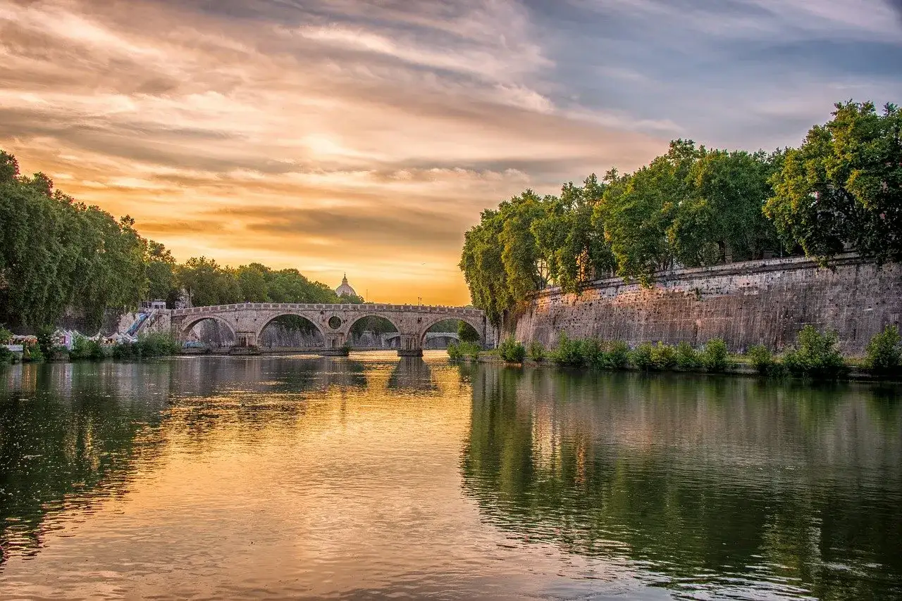 Ponte Sisto sul Tevere, con il tramonto che tinge il cielo e il fiume di colori caldi, un'atmosfera magica a Trastevere.