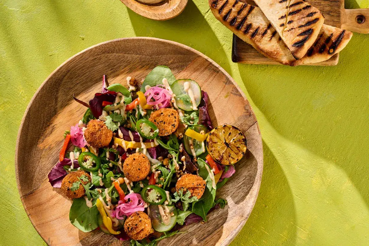 Kolorowa sałatka z falafelami, warzywami i grillowaną cytryną, polana sosem tahini. Idealna do przygotowania z wodą, by uzyskać idealne proporcje.