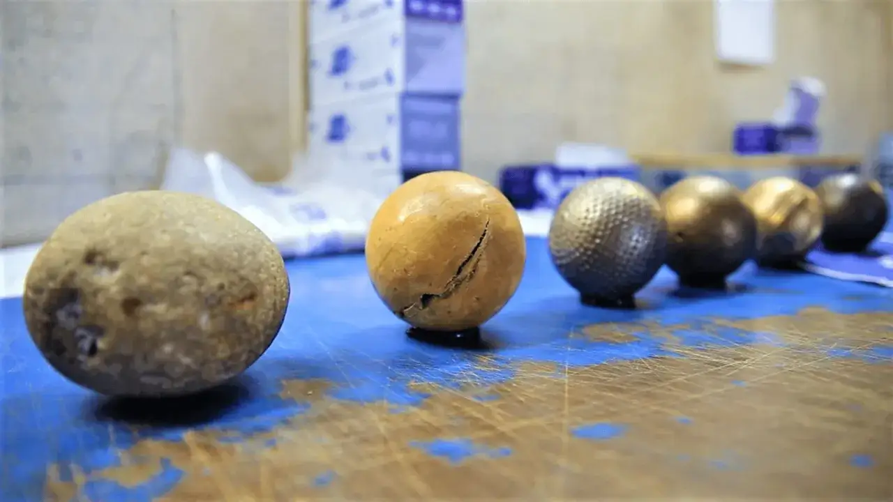 Des boules de pétanque brutes et finies, montrant les étapes de la fabrication.