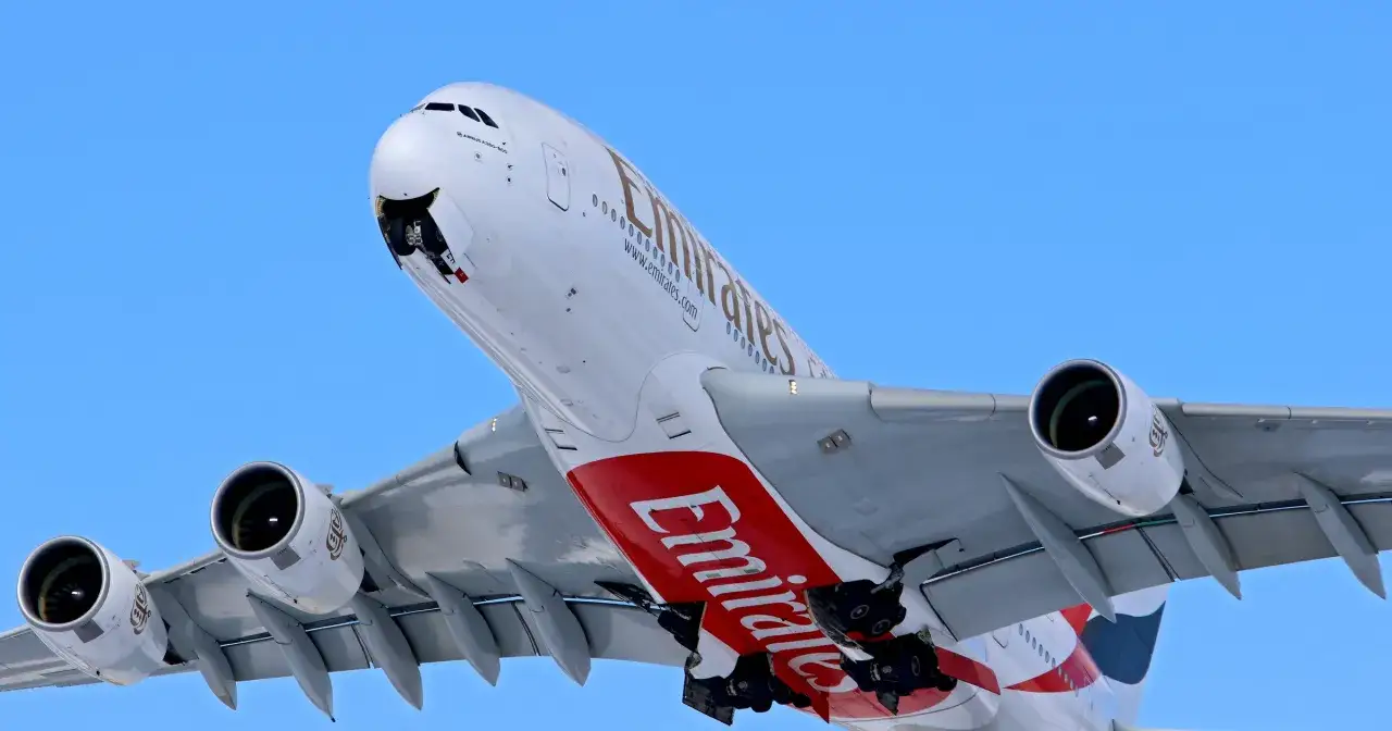 Ogromny samolot Emirates z wysuniętym podwoziem wznosi się na błękitne niebo. Marzysz o podróży do Jordanii? Loty Emirates mogą być Twoją szansą!