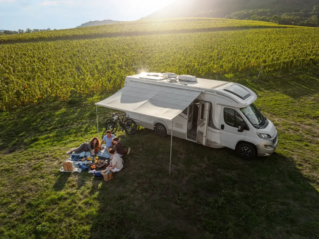 Familie genie&szlig;t Picknick neben Wohnmobil in Weinbergen. Perfekter Urlaub f&uuml;r Camping Tschechien.