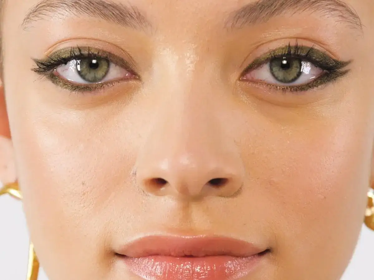 Occhi verdi esaltati da un trucco audace con eyeliner verde scuro e mascara.